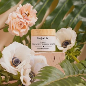 Può includere: Un barattolo di vetro trasparente di balsamo di sego biologico Ginger Lily con un coperchio color legno chiaro. L'etichetta bianca riporta il testo nero Ginger Lily, Organic DECADENT TALLOW BALM e Limited edition con una piccola icona a cuore.