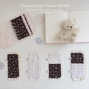 Op de afbeelding: Een collectie planner-insteekhoezen met bloemmotieven in donkerbruin en lichtroze, afgewerkt met witte kanten randen en metalen ringen. De set bevat een grotere stoffen organizer met een rits en een kleine pluche beer.