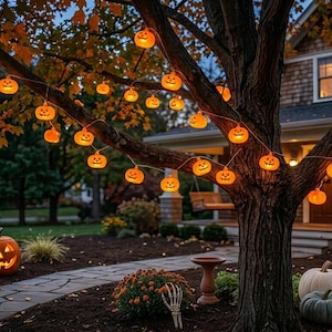 May include: A string of glowing orange jack-o'-lantern lights draped across the branches of a large tree. The small, illuminated pumpkin-shaped bulbs cast a warm light, while several larger carved pumpkins sit on the ground near the tree trunk.