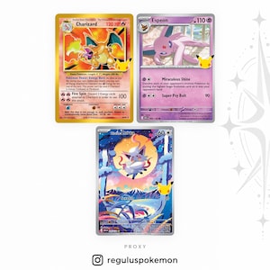 Puede incluir: Tres cartas coleccionables de Pokémon que muestran a Charizard con 120 HP, Espeon con 110 HP y Hisuian Zorua con 60 HP. Cada carta presenta ilustraciones coloridas de personajes, estadísticas de ataque y un logo del 25 aniversario.