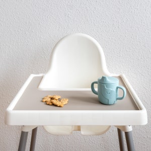 Auf einem IKEA Antilop Hochstuhl liegt eine beiges Platzset aus Silikon.