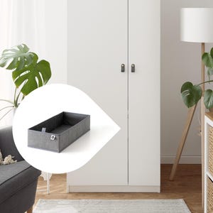 Può includere: Un contenitore portaoggetti in tessuto grigio di forma rettangolare. Il contenitore ha un bordo grigio scuro e un piccolo logo sul davanti. Il contenitore è progettato per organizzare oggetti ed è mostrato davanti a un armadio bianco.