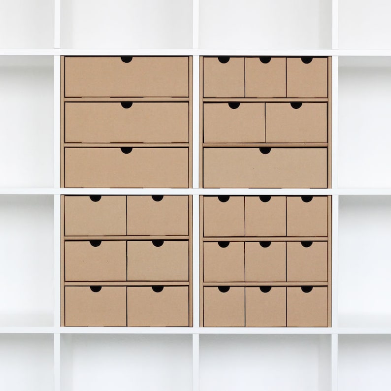 Kallax Schubladeneinstäze aus Pappe für ein Ikea Kallax Regal. 4 Fächer sind in einem weißen Kallax Regal mit jeweils 4 Papp-Einsätzen mit bis zu 9 kleinen Schubladen gefüllt.