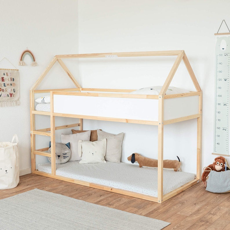 Ein Kinderzimmer, in dem man das Kura Bett von Ikea umfänglich mit Kuscheltieren und Kissen dekoriert sieht.