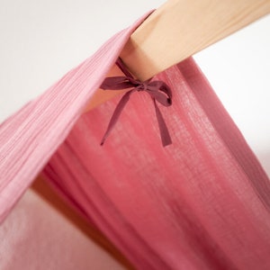 Detailaufnahme von einem rosa Baldachin für ein Kura Hausbett aus Musselinstoff.