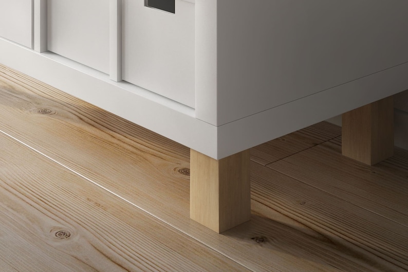 Ein weißes Ikea Kallax Regal steht auf quadratischen Möbelfüßen aus Buchenholz.