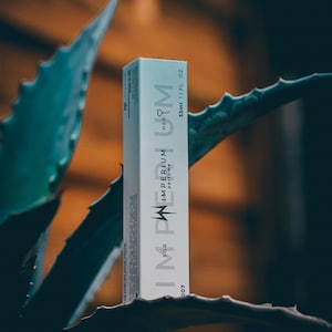 May include: A rectangular white perfume box labeled IMPERIUM FOR HER with a lightning bolt graphic. The packaging displays the text 33ml 1.1 FL. OZ. and includes small printed details on the side panel, presented in a vertical orientation.