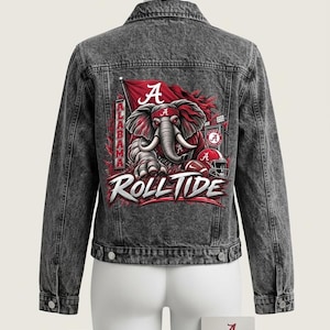 May include: A charcoal grey acid-wash denim jacket featuring a large graphic on the back. The design displays a red elephant mascot, a football helmet, and the text "ALABAMA" and "ROLL TIDE" in white and red lettering. The jacket has a collar.