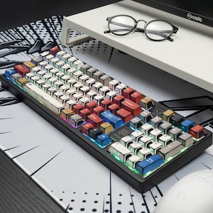 May include: A mechanical keyboard featuring custom keycaps with a comic book aesthetic, including black outlines and varied colors like red, blue, and white. The keys display letters, numbers, and symbols, with a black frame and integrated RGB lighting.