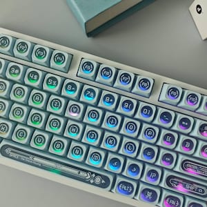 May include: A mechanical keyboard with light blue keycaps featuring circular symbols and letters. The keys are backlit with a gradient of green, blue, and purple light. The space bar includes the text "SPACE - The Time Is Flowing".