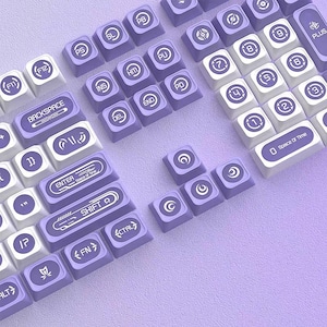 May include: A mechanical keyboard keycap set featuring a lavender and white color scheme. The keys display various symbols, numbers, and text including "BACKSPACE", "ENTER Space Of Time", "SHIFT", "FN", "CTRL", and "0 Space Of Time".