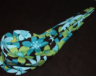 Könnte beinhalten: Eine Stofftasche mit einem Blumenmuster in Blautönen, Grün- und Brauntönen. Die Tasche ist gefaltet und liegt auf einer dunklen Oberfläche.