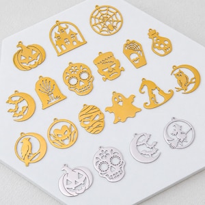 Può includere: Una collezione di ciondoli in metallo color oro e argento con vari disegni a tema Halloween, tra cui zucche, teschi, fantasmi, pipistrelli, una casa stregata, una ragnatela, una mummia, una strega su una scopa, un gatto, un gufo e una pozione.