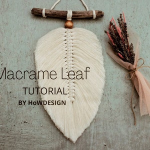 May include: A white macrame leaf wall hanging with a wooden dowel and a gold bead at the top. The text "Macrame Leaf TUTORIAL BY HOWDESIGN" is below the hanging.