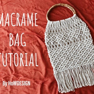 Pode incluir: Uma bolsa de macramé branca com alça de madeira e franjas. A bolsa está sobre um fundo de tecido vermelho. O texto "MACRAME BAG TUTORIAL" está escrito em branco no tecido. O texto "By HOWDESIGN" está escrito em branco abaixo do texto do tutorial.