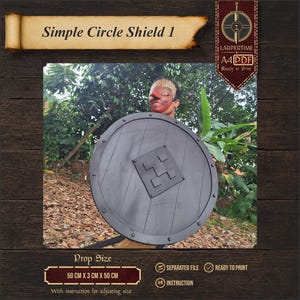 Puede incluir: Un escudo circular gris oscuro con un resalte cuadrado central y remaches en el perímetro. El escudo presenta una textura de tablones y mide 50 cm x 3 cm x 50 cm. El texto "Simple Circle Shield 1" y "LARPERTIME A4 PDF Ready to Print" es visible.