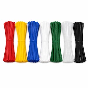 Op de afbeelding: Zeven bundels bindstrips op een rij, elk vastgezet met een bandje in het midden. De kleuren van links naar rechts zijn rood, geel, blauw, wit, groen, transparant en zwart. Elke bundel bestaat uit meerdere dunne, platte en flexibele plastic strips.