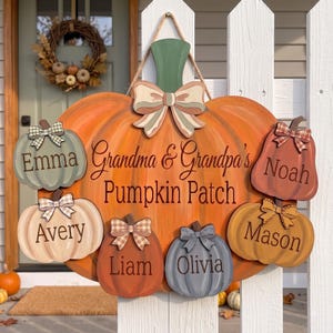 May include: A large orange wooden pumpkin sign with a green stem and a decorative bow, featuring the text "Grandma & Grandpa's Pumpkin Patch". Six smaller pumpkins in various colors are attached, each personalized with the names Emma, Noah, Avery, Liam, Olivia, and Mason.
