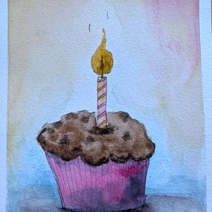 May include: A watercolor painting of a chocolate muffin in a pink paper liner with a single lit birthday candle on top. The candle has a yellow flame and a striped pattern. The background features a soft gradient of light orange and blue tones.