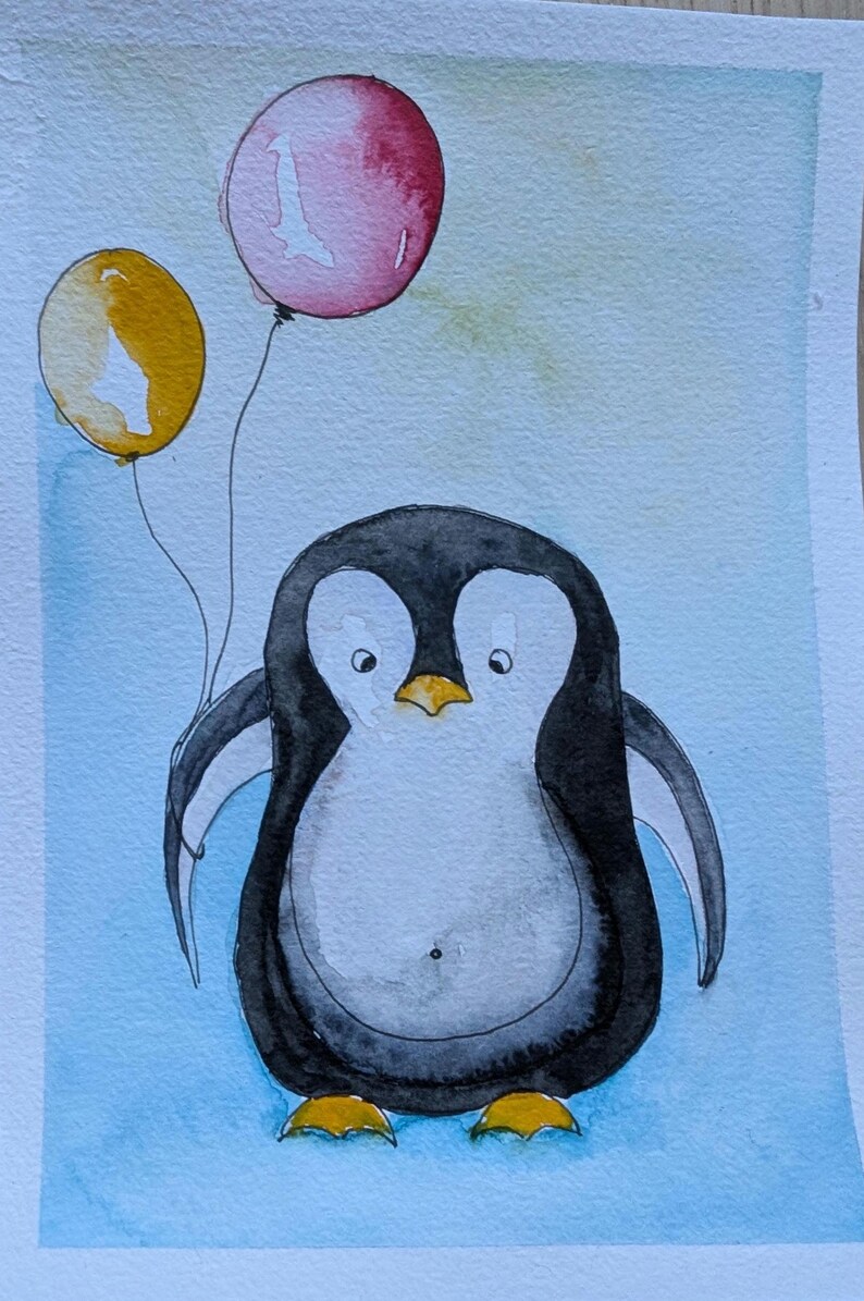 May include: A watercolor painting of a penguin with a black and white body, yellow feet, and a yellow beak. The penguin is holding two balloons, one yellow and one pink, against a light blue background with soft, blended watercolor washes.