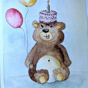 May include: A watercolor illustration of a brown bear with a light-colored belly, holding a yellow balloon and a red balloon. The bear has a small cake with a lit candle on its head and the text Happy Birthday written in black ink at the bottom.