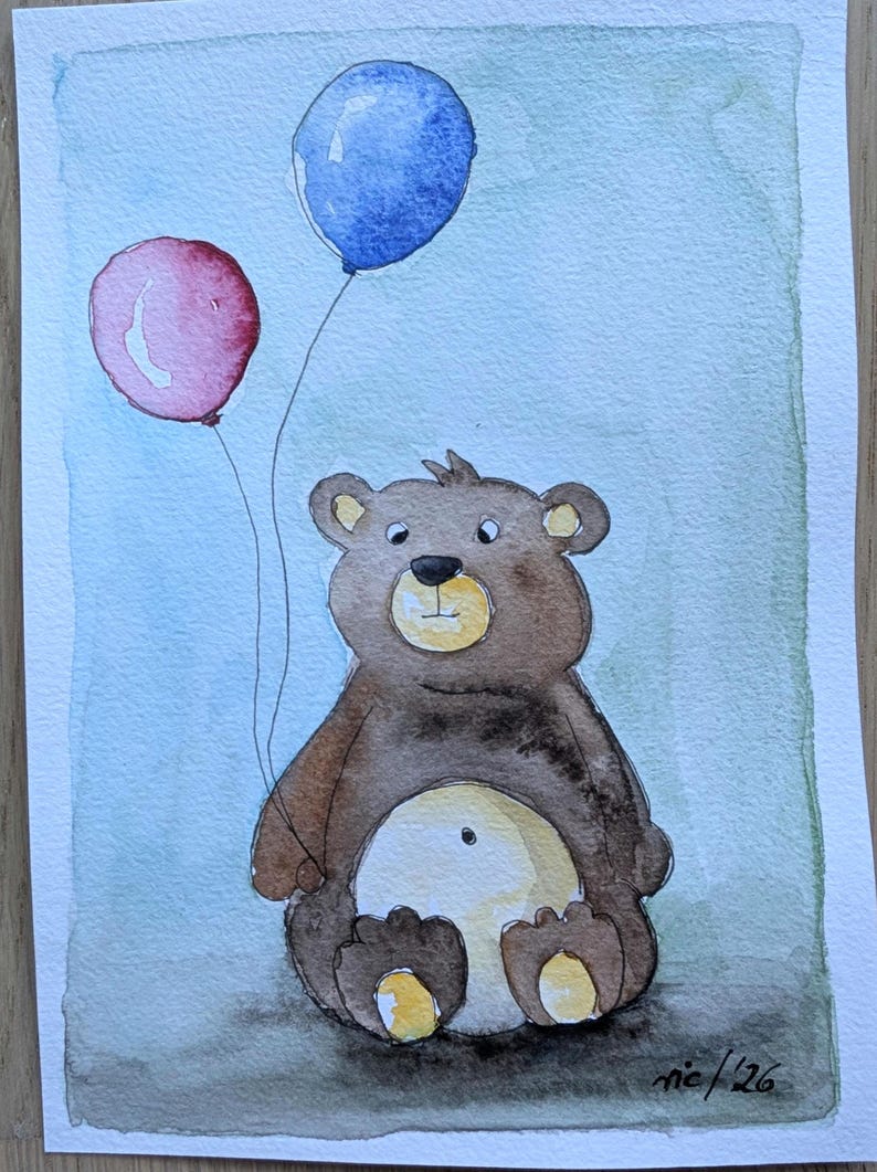 May include: A watercolor painting on paper depicting a brown bear sitting down and holding two balloons, one red and one blue. The bear has a light tan belly and muzzle. The background is a soft, blended wash of light blue and green. Signed 'nic '26'.