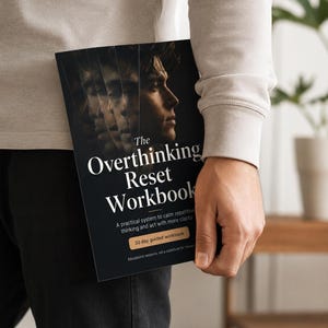 Op de afbeelding: Een zwart werkboek getiteld The Overthinking Reset Workbook met een gelaagd portret van een persoon op de omslag. De tekst luidt A practical system to calm repetitive thinking and act with more clarity en 30 day guided workbook.