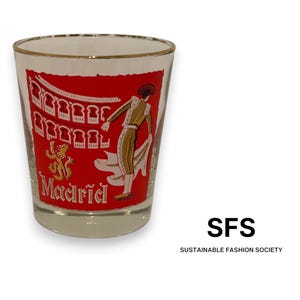 May include: A clear glass tumbler with a gold rim featuring a red graphic print of a bullfighter in an arena, a lion emblem, and the text Madrid. The design is set against a red background on the exterior of the glass, which is transparent.