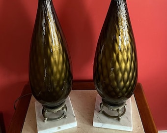 May include: A pair of gold and brown glass table lamps with white marble bases. The lamps have a textured, diamond-like pattern.