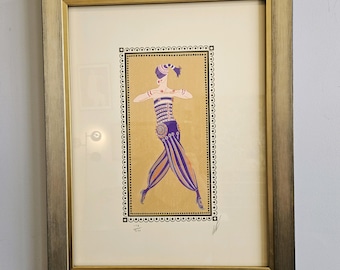 May include: A framed print of a colourful illustration of a woman in a purple and gold costume. The woman is dancing with her arms outstretched. The print is surrounded by a gold frame.