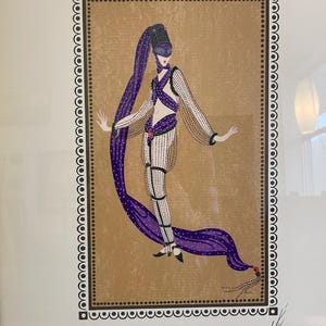 May include: A framed print of a woman in a purple and black costume with a mask. The woman is standing in a gold frame with a black and white border. The print is numbered 34/308.