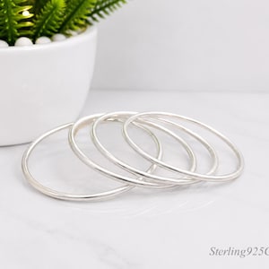 May include: A set of four thin, polished silver bangles arranged in an overlapping stack. Each bangle features a smooth, rounded surface with a reflective metallic finish. The text Sterling925Crafts! is visible in the bottom right corner.