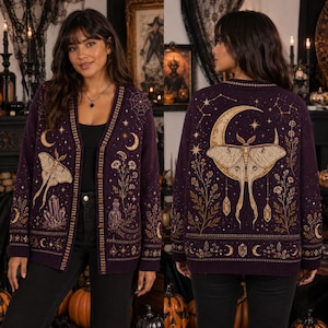 May include: A dark purple long-sleeve cardigan featuring a large moth and crescent moon graphic on the back. The front and back are decorated with gold-toned illustrations of crystals, wildflowers, spiderwebs, and celestial motifs throughout.