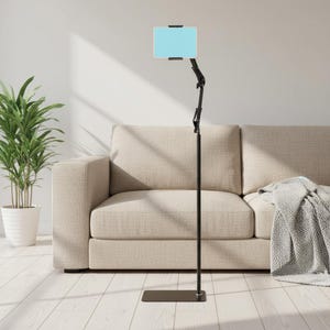 May include: A black floor stand featuring a rectangular base, a vertical pole, and an adjustable articulated arm. The top of the arm holds a light blue tablet device securely in place with black clamps, positioned at an elevated height.