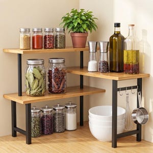 May include: A tiered corner shelf unit with a black metal frame and light wood shelves. It holds various glass spice jars, oil bottles, a potted green plant, a stack of white bowls, a metal whisk, and a small stainless steel measuring cup.