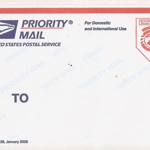 May include: A white Priority Mail label from the United States Postal Service with the text "PRIORITY MAIL" and "UNITED STATES POSTAL SERVICE" in blue. The label also includes the text "For Domestic and International Use" and a red logo with a globe and the text "INTERNATIONAL EXPRESS PRIORITY" in white.