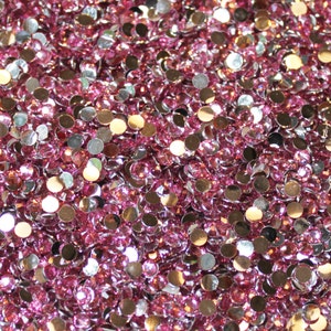 May include: A large quantity of pink and silver rhinestones. The rhinestones are small and round, and they are scattered randomly.