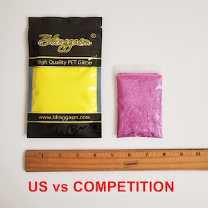 Op de afbeelding: Twee kleine zakjes glitter, een gele en een roze, worden naast een liniaal getoond. De zakjes zijn gelabeld met "Blinggasm High Quality PET Glitter" en "www.blinggasm.com". De tekst "US vs COMPETITION" staat onder de liniaal.