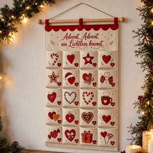 May include: A cream-colored fabric advent calendar hanging from a wooden rod with a string. It features red scalloped trim and the text "Advent, Advent, ein Lichtlein brennt". The calendar has twenty pockets, each decorated with red holiday-themed icons.