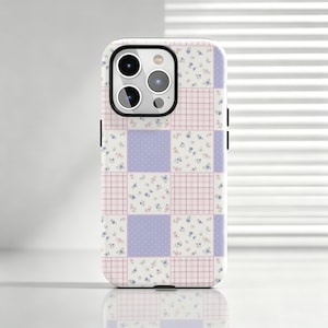 Könnte beinhalten: Eine Smartphone-Hülle mit einem Patchwork-Design aus abwechselnden Quadraten. Das Muster besteht aus hellvioletten Quadraten mit weißen Punkten, rosa-weiß karierten Quadraten und weißen Quadraten mit kleinen blauen und rosa Blumenmustern.