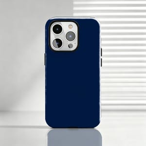 May include: A solid dark navy blue smartphone case featuring a rectangular cutout for the camera module. The case has a smooth, matte finish and covers the back and sides of the device, with precise openings for the triple camera lens array.