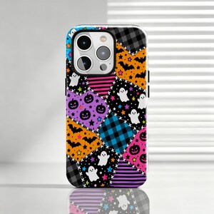 May include: A smartphone case featuring a colourful patchwork design with various Halloween-themed patterns including white ghosts, black bats, purple jack-o'-lanterns, orange stars, and sections of black and white plaid, blue plaid, and pink stripes.