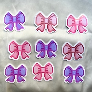 Op de afbeelding: Negen pixel art strik stickers in roze, paars en rood. De strikken zijn gerangschikt in drie rijen van drie.