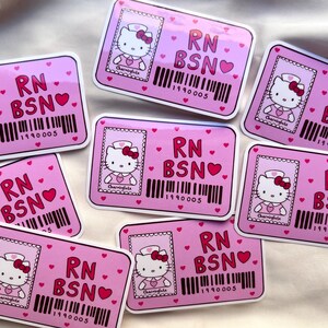 Puede incluir: Nueve pegatinas rosas con una imagen de dibujos animados de Hello Kitty vestida de enfermera. Cada pegatina tiene el texto "RN BSN" y un c&oacute;digo de barras con el n&uacute;mero "1990005".