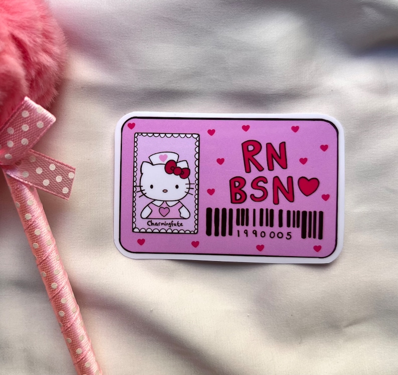 Puede incluir: Pegatina rosa y blanca con un dibujo animado de Hello Kitty vestida de enfermera. La pegatina dice "RN BSN" con un coraz&oacute;n y un c&oacute;digo de barras que dice "1990005".