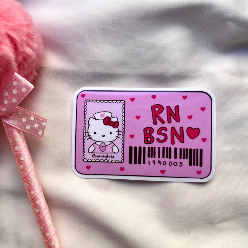 Puede incluir: Insignia de identificaci&oacute;n de Hello Kitty rosa y blanca con el texto "RN BSN" y un coraz&oacute;n rojo. La insignia presenta una imagen de dibujos animados de Hello Kitty vestida de enfermera.