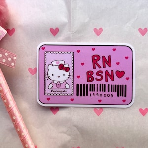 Puede incluir: Pegatina rosa y roja de Hello Kitty con un uniforme de enfermera y una placa que dice "RN BSN" con un peque&ntilde;o coraz&oacute;n. La pegatina tiene un c&oacute;digo de barras con el n&uacute;mero 199005.