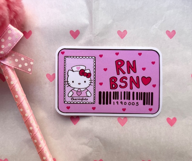 Puede incluir: Pegatina rosa y roja de Hello Kitty con un uniforme de enfermera y una placa que dice "RN BSN" con un peque&ntilde;o coraz&oacute;n. La pegatina tiene un c&oacute;digo de barras con el n&uacute;mero 199005.