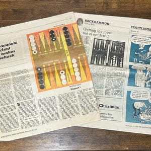 May include: Two pages of a vintage newspaper featuring an article titled Backgammon: an ancient game makes a comeback by Ted Barr. The layout includes a colorful diagram of a backgammon board, text columns, and a blue-toned comic strip titled Prattlings.