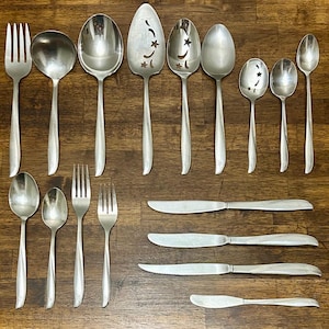 May include: A stainless steel flatware set consisting of a large serving fork, a ladle, two large serving spoons, a cake server with star cutouts, a slotted spoon with star cutouts, three dinner spoons, two dinner forks, three knives, and a butter knife.